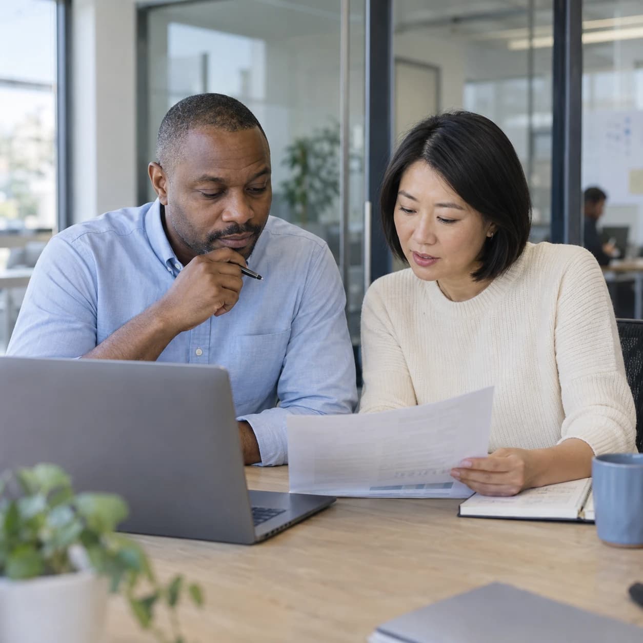 Two colleagues reviewing a proposal together at a desk in a modern office
